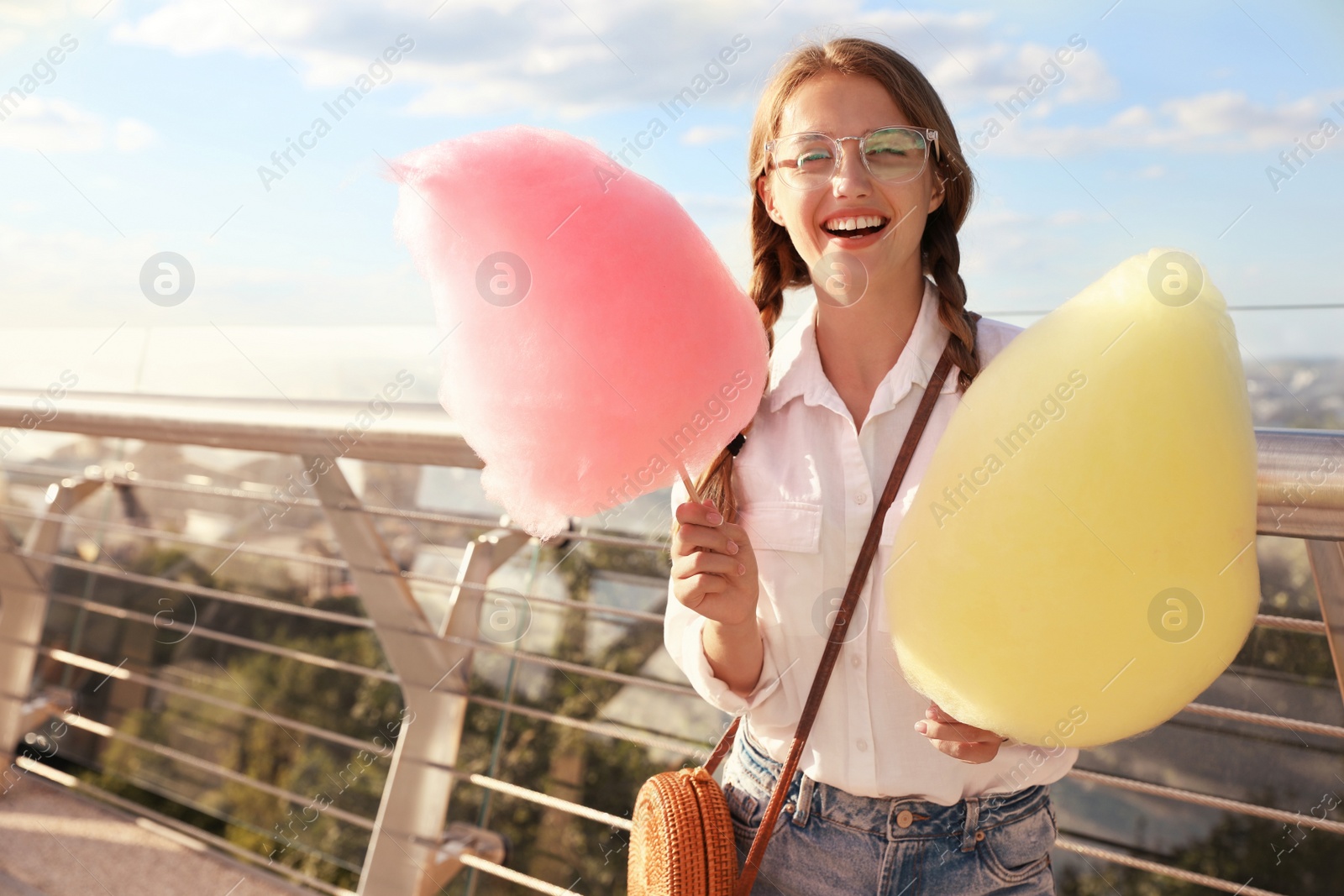 Photo of Young woman with cotton candies outdoors on sunny day. Space for text