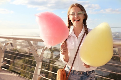Photo of Young woman with cotton candies outdoors on sunny day. Space for text