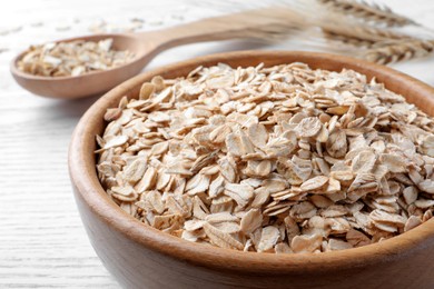 Photo of Oatmeal, bowl and spoon on white table, closeup