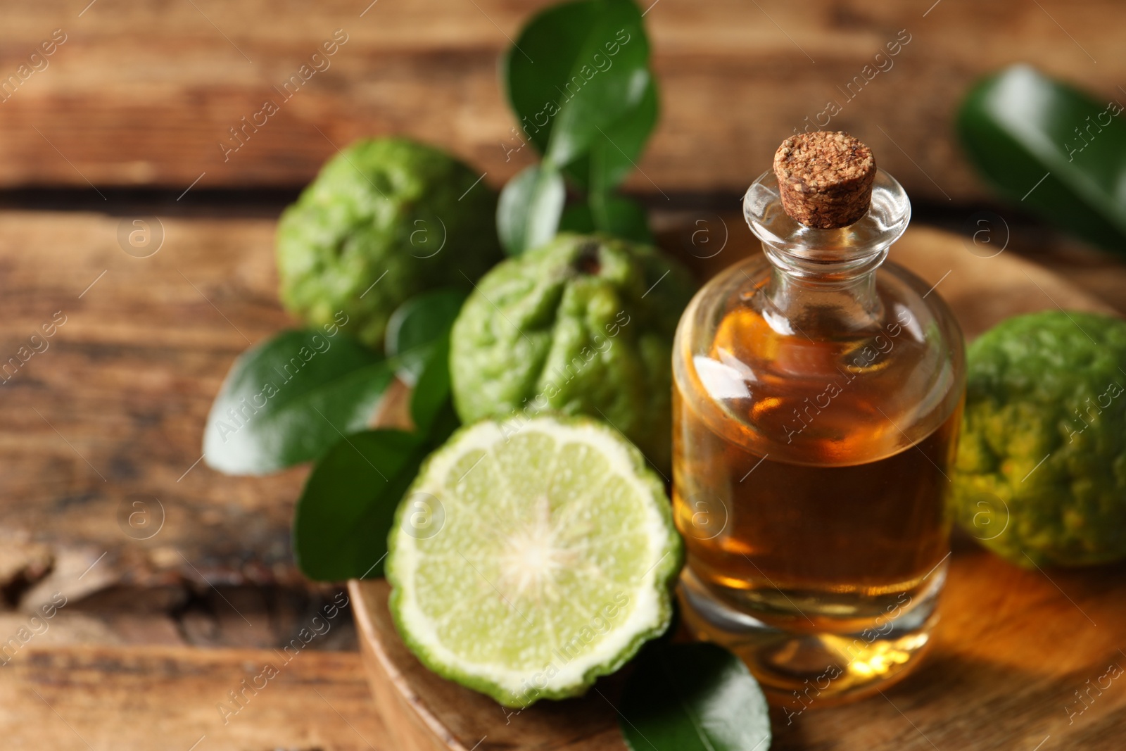 Photo of Glass bottle of bergamot essential oil on wooden table, closeup. Space for text