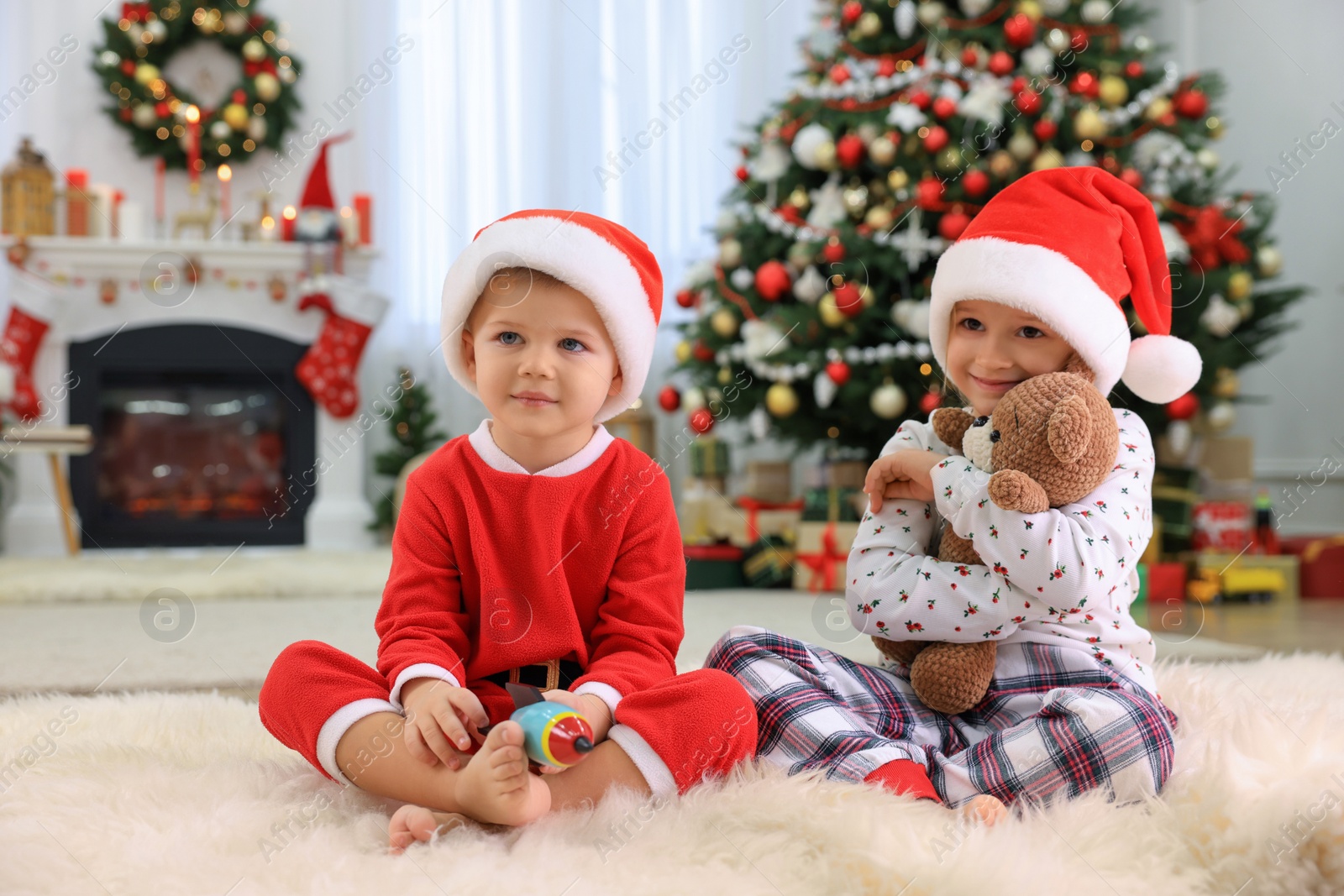 Photo of Cute little children with toys in room decorated for Christmas