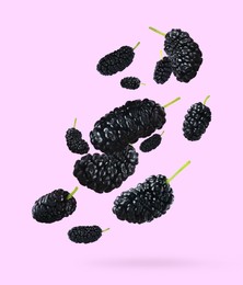 Fresh ripe black mulberries falling on lilac background