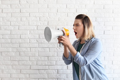 Photo of Portrait of young woman using megaphone near brick wall. Space for text