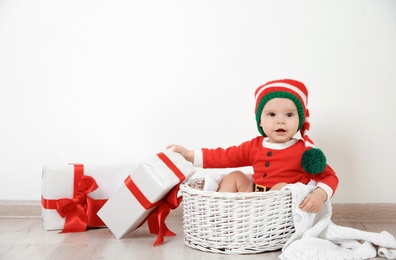 Photo of Cute little baby wearing Christmas costume in basket at home