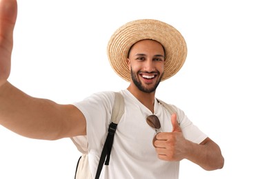Photo of Smiling young man in straw hat taking selfie and showing thumbs up on white background