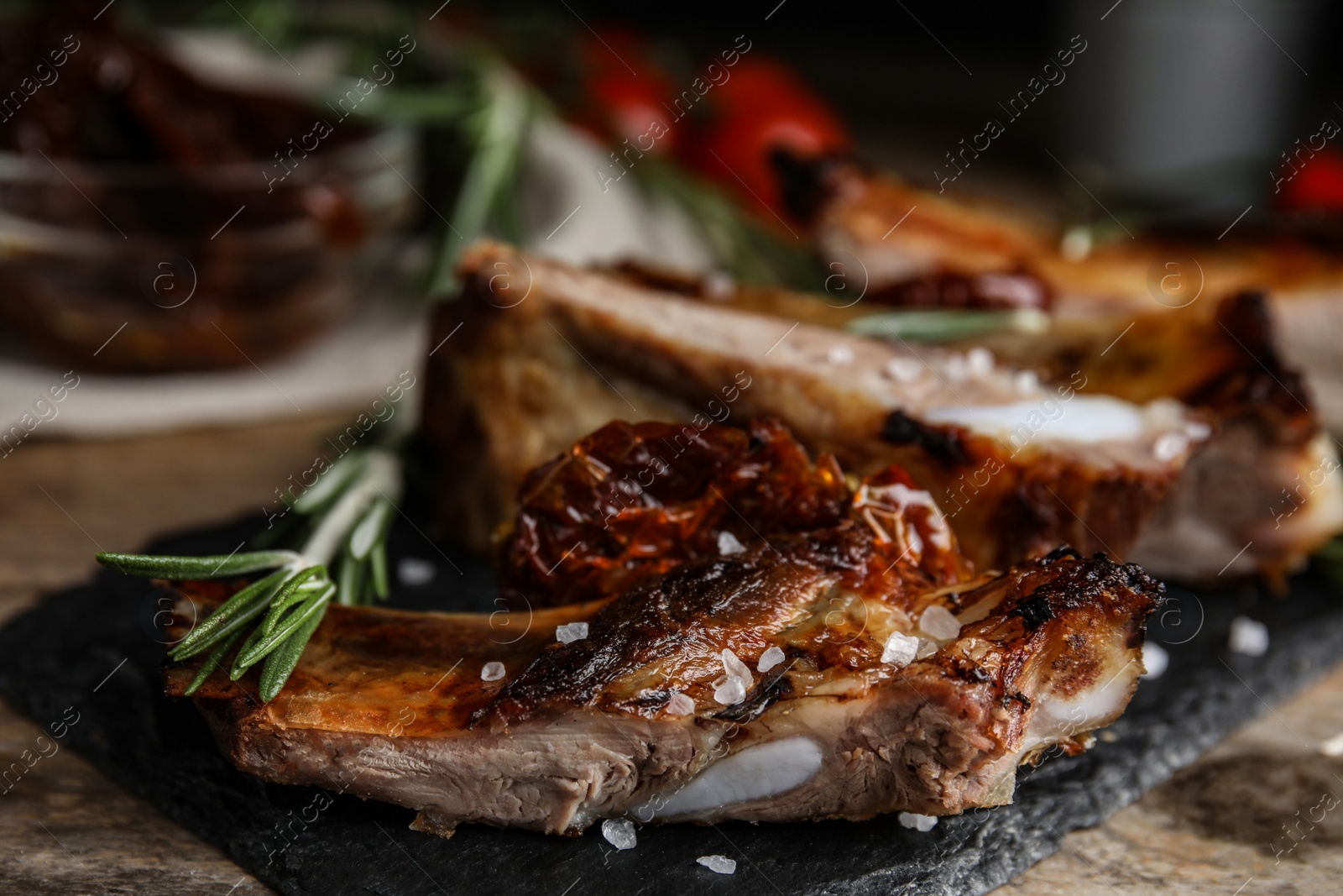 Photo of Tasty grilled ribs with rosemary on wooden table, closeup