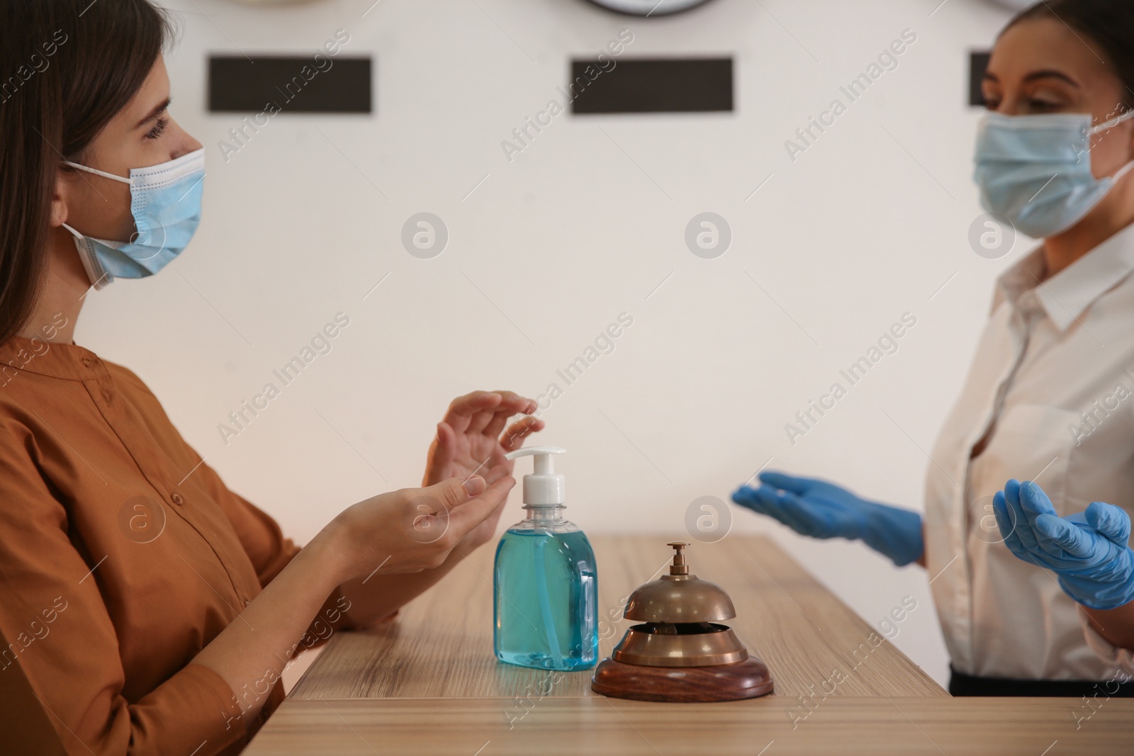 Photo of Woman applying antiseptic gel at hotel reception