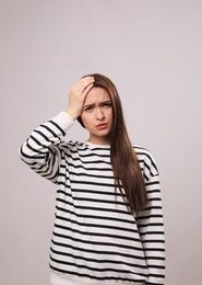 Woman suffering from headache on light grey background. Cold symptoms