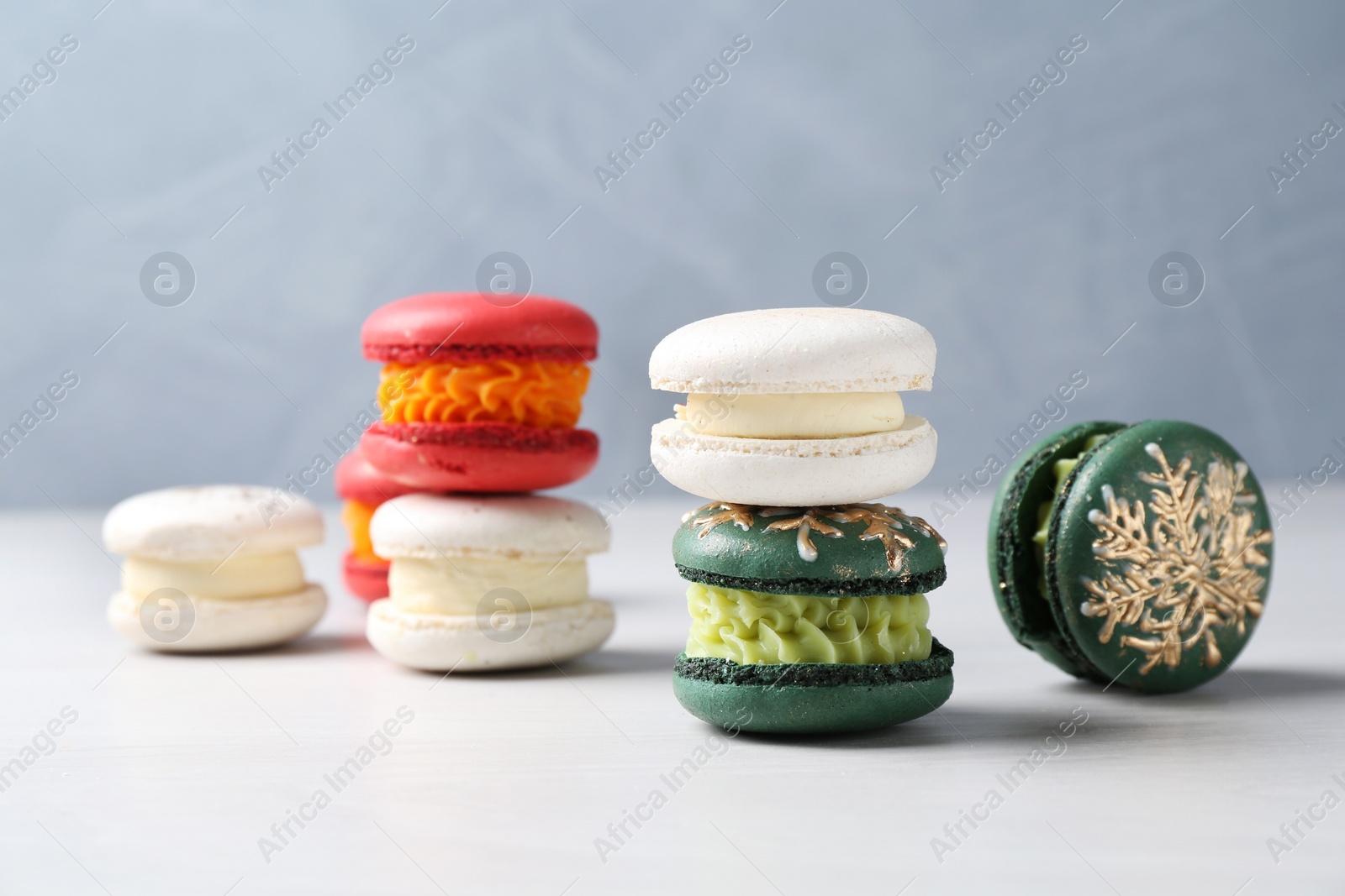 Photo of Different decorated Christmas macarons on white table, closeup