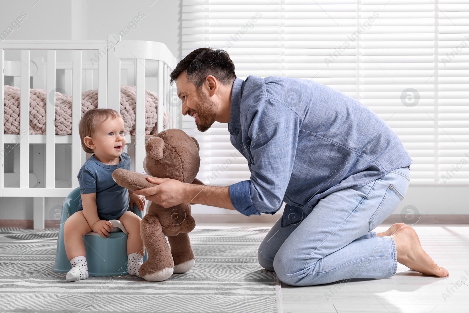 Photo of Father training his child to sit on baby potty indoors