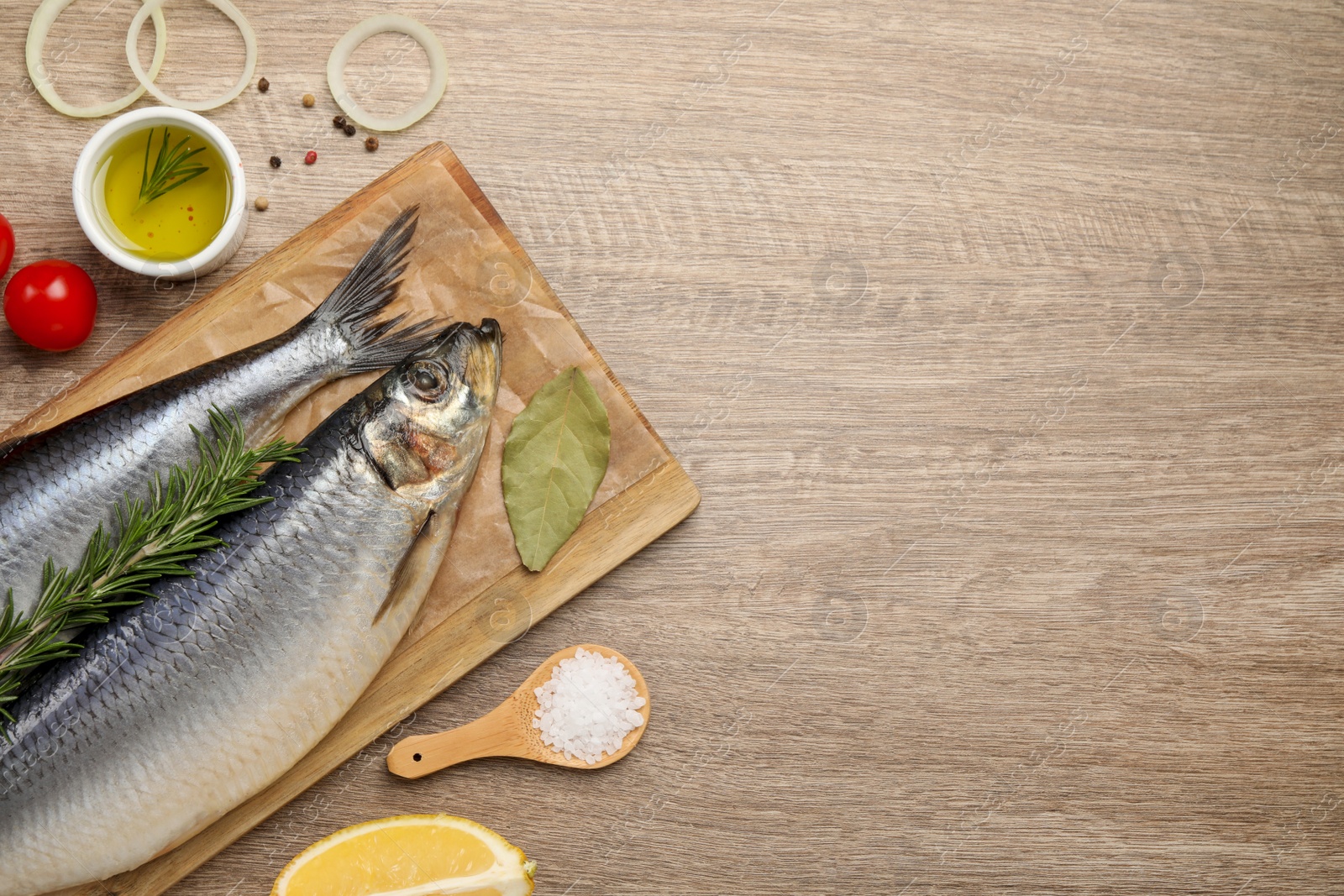 Photo of Delicious salted herrings and ingredients on wooden table, flat lay. Space for text