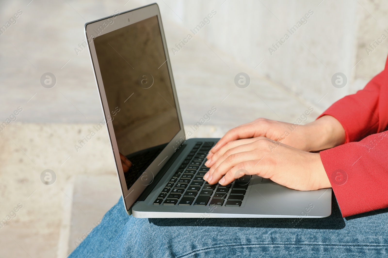 Image of Young woman working on laptop outdoors, closeup