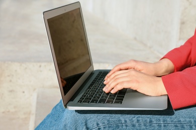 Image of Young woman working on laptop outdoors, closeup