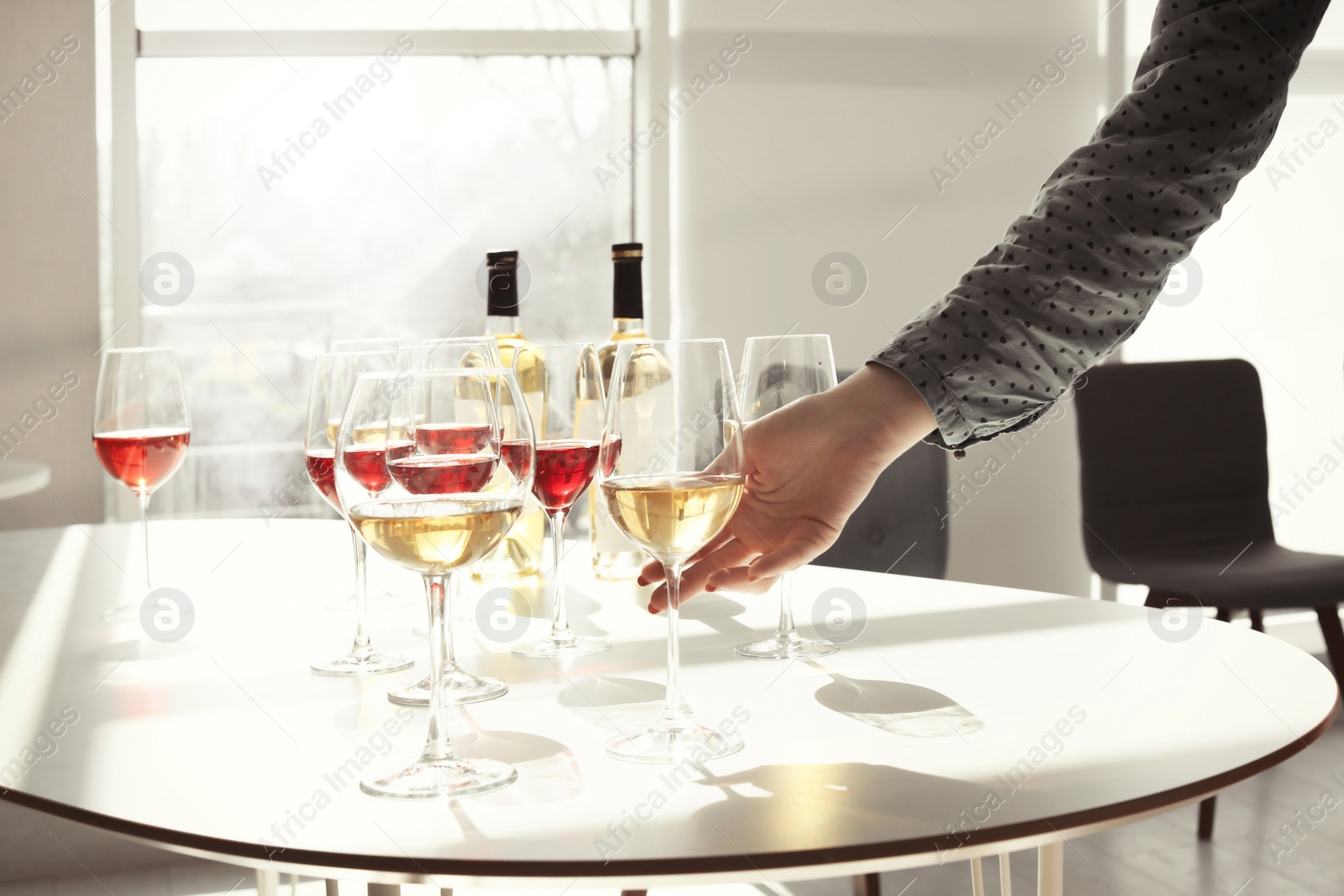 Photo of Woman taking glass of wine from table indoors