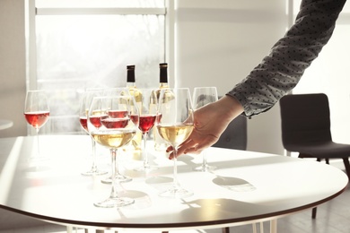 Woman taking glass of wine from table indoors