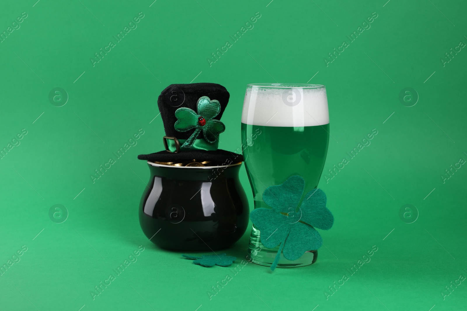 Photo of St. Patrick's day party. Green beer, leprechaun hat, pot of gold and decorative clover leaves on green background