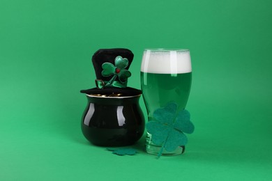 Photo of St. Patrick's day party. Green beer, leprechaun hat, pot of gold and decorative clover leaves on green background