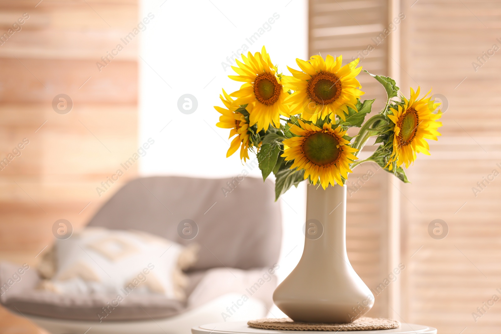 Photo of Vase with beautiful yellow sunflowers on table in room, space for text