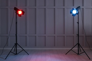 Photo of Bright red and blue spotlights near wall indoors, space for text