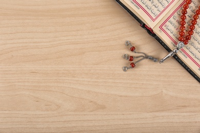 Photo of Muslim prayer beads, Quran and space for text on wooden background, top view