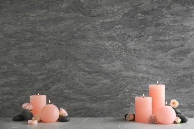 Photo of Composition of burning candles, spa stones and flowers on table. Space for text