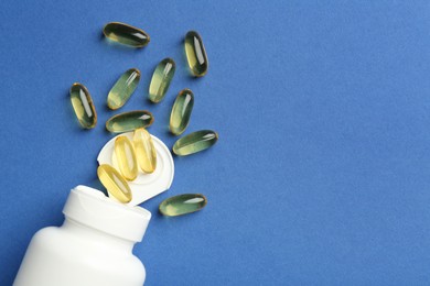 Bottle of vitamin capsules on blue background, top view. Space for text