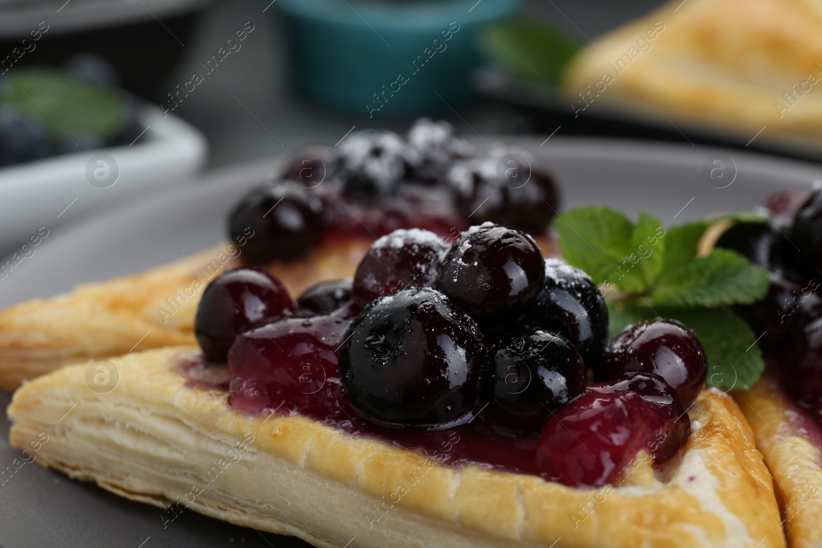 Photo of Fresh tasty puff pastry with sugar powder, jam, sweet berries and mint, closeup