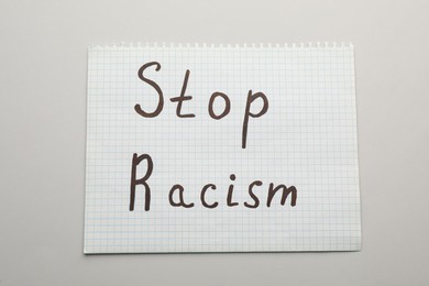 Photo of Paper sheet with phrase Stop Racism on light table, top view