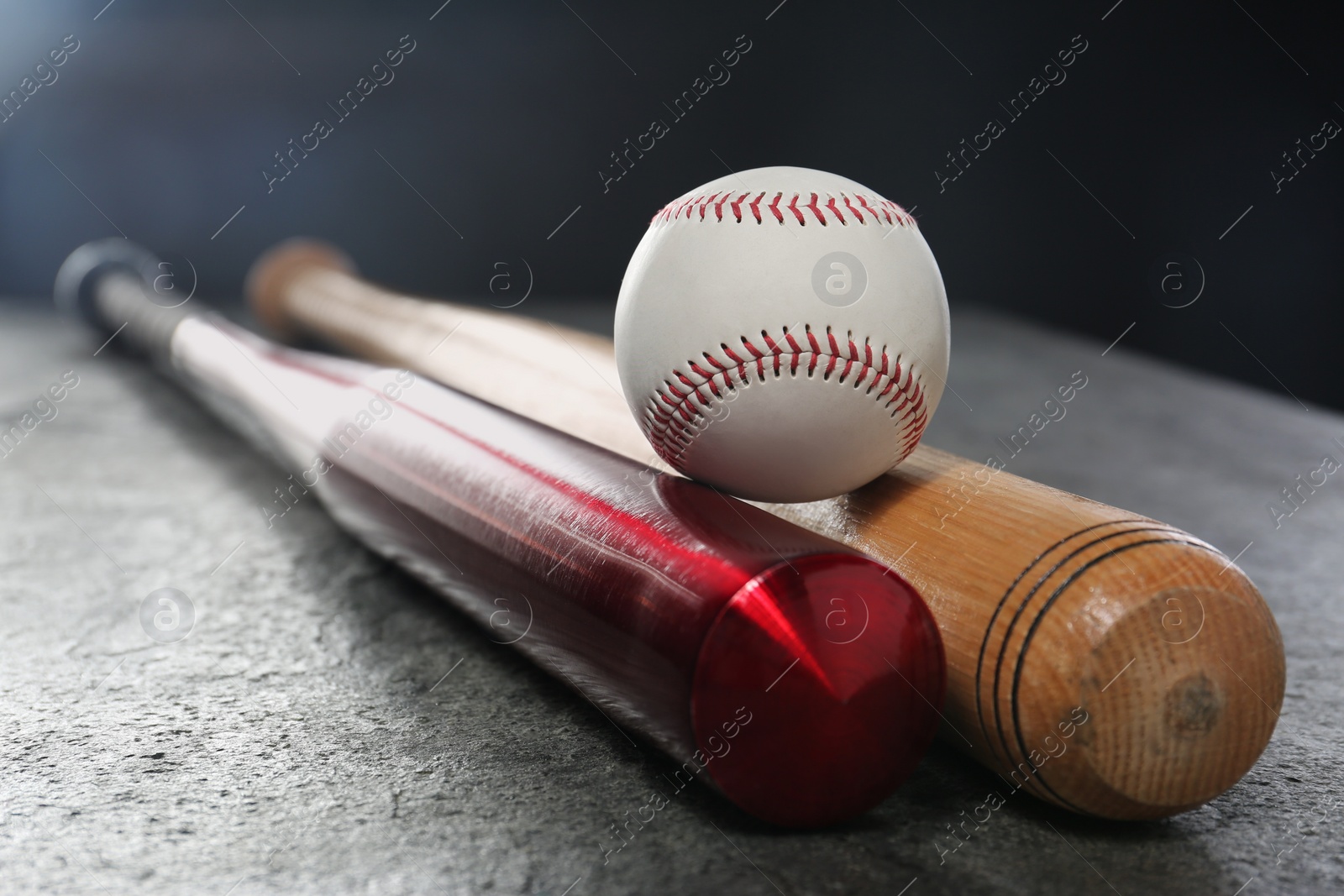 Photo of Baseball bats and ball on grey table, closeup