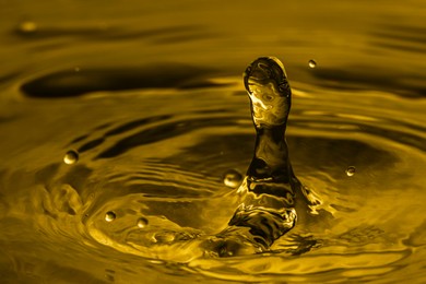 Image of Splash of golden oily liquid with drops as background, closeup