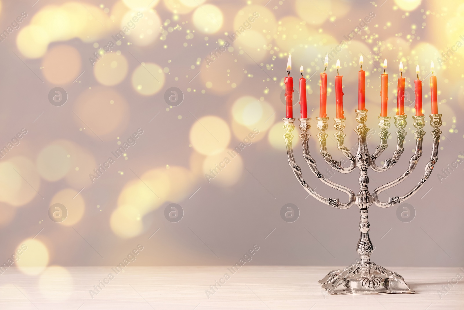 Image of Silver menorah with burning candles on table against light background, space for text. Hanukkah celebration