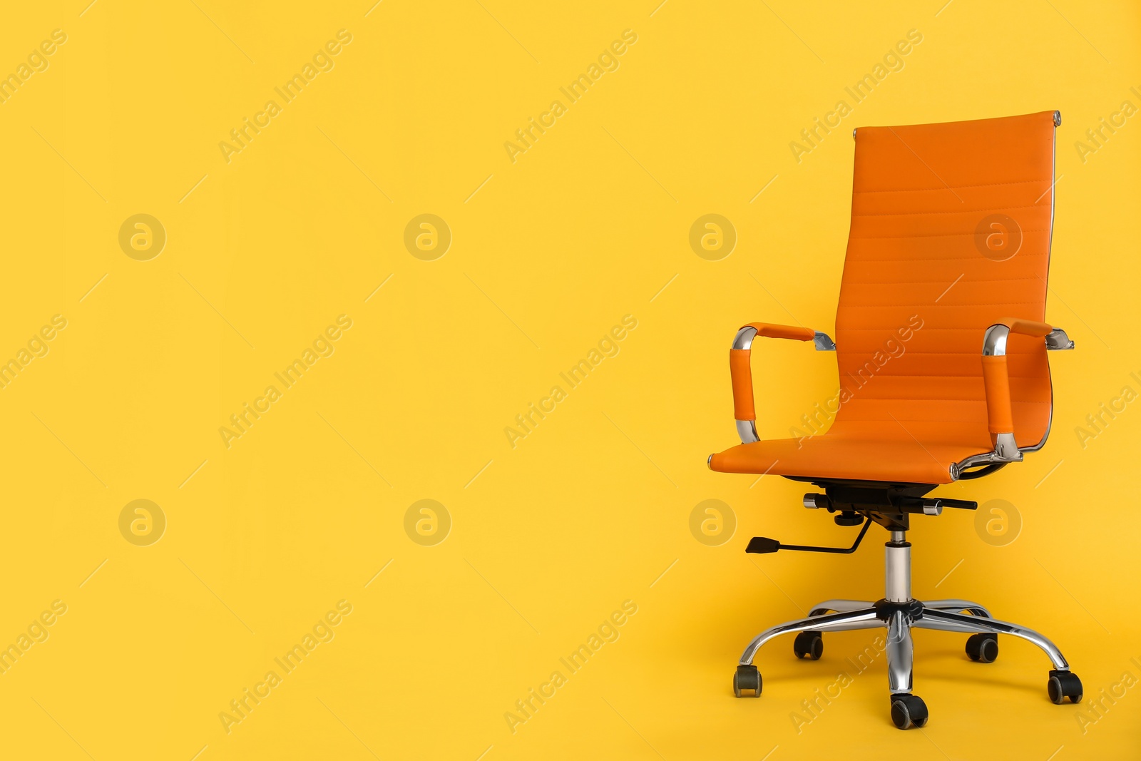 Photo of Modern office chair on yellow background. Space for text