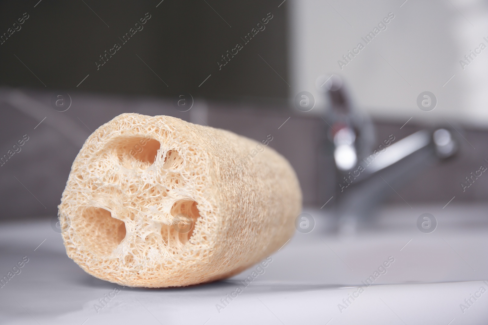 Photo of Natural loofah sponge on washbasin in bathroom, closeup