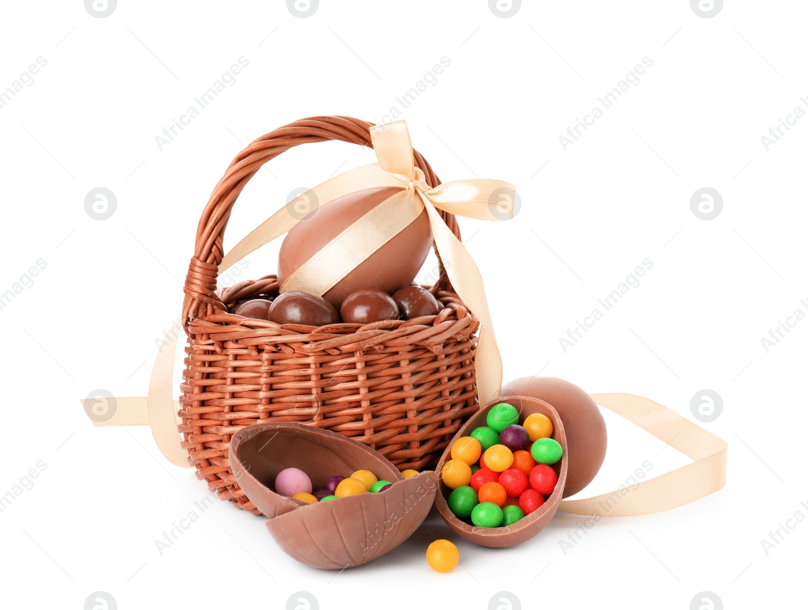 Photo of Wicker basket with tasty chocolate eggs and colorful candies on white background