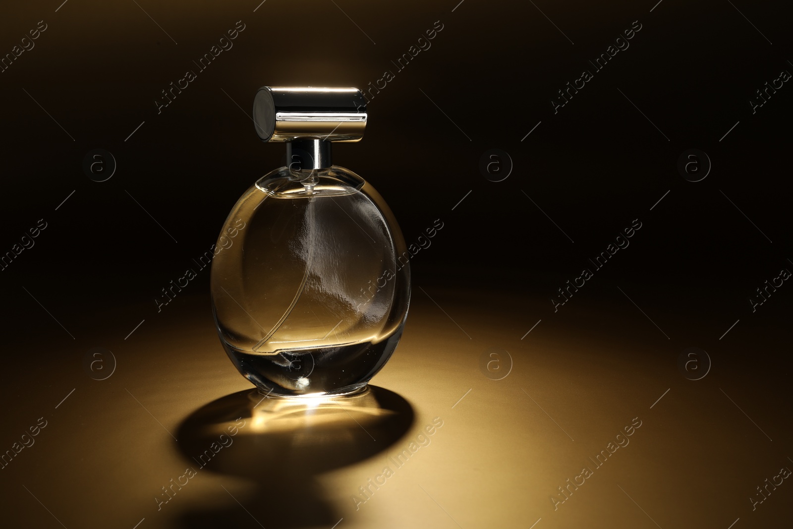 Photo of Luxury women's perfume. Sunlit glass bottle on golden background, space for text