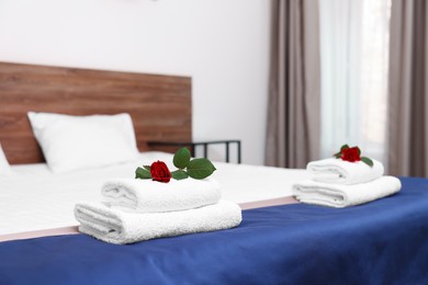 Photo of Clean folded towels with flowers on bed in hotel room