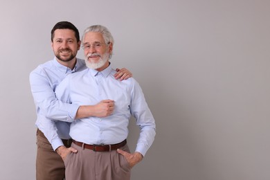 Photo of Happy son and his dad on gray background, space for text
