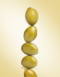 Image of Stack of whole olives on pastel gold background
