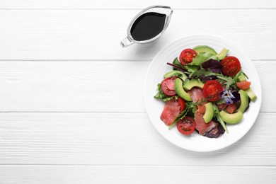 Photo of Tasty soy sauce and plate of salad on white wooden table, flat lay. Space for text