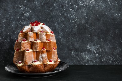 Photo of Delicious Pandoro Christmas tree cake with powdered sugar and berries on black table. Space for text