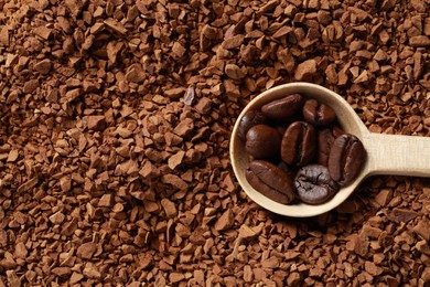 Photo of Spoon with roasted beans on instant coffee, top view