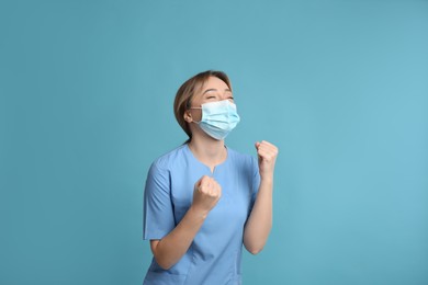 Emotional doctor with protective mask on light blue background. Strong immunity concept