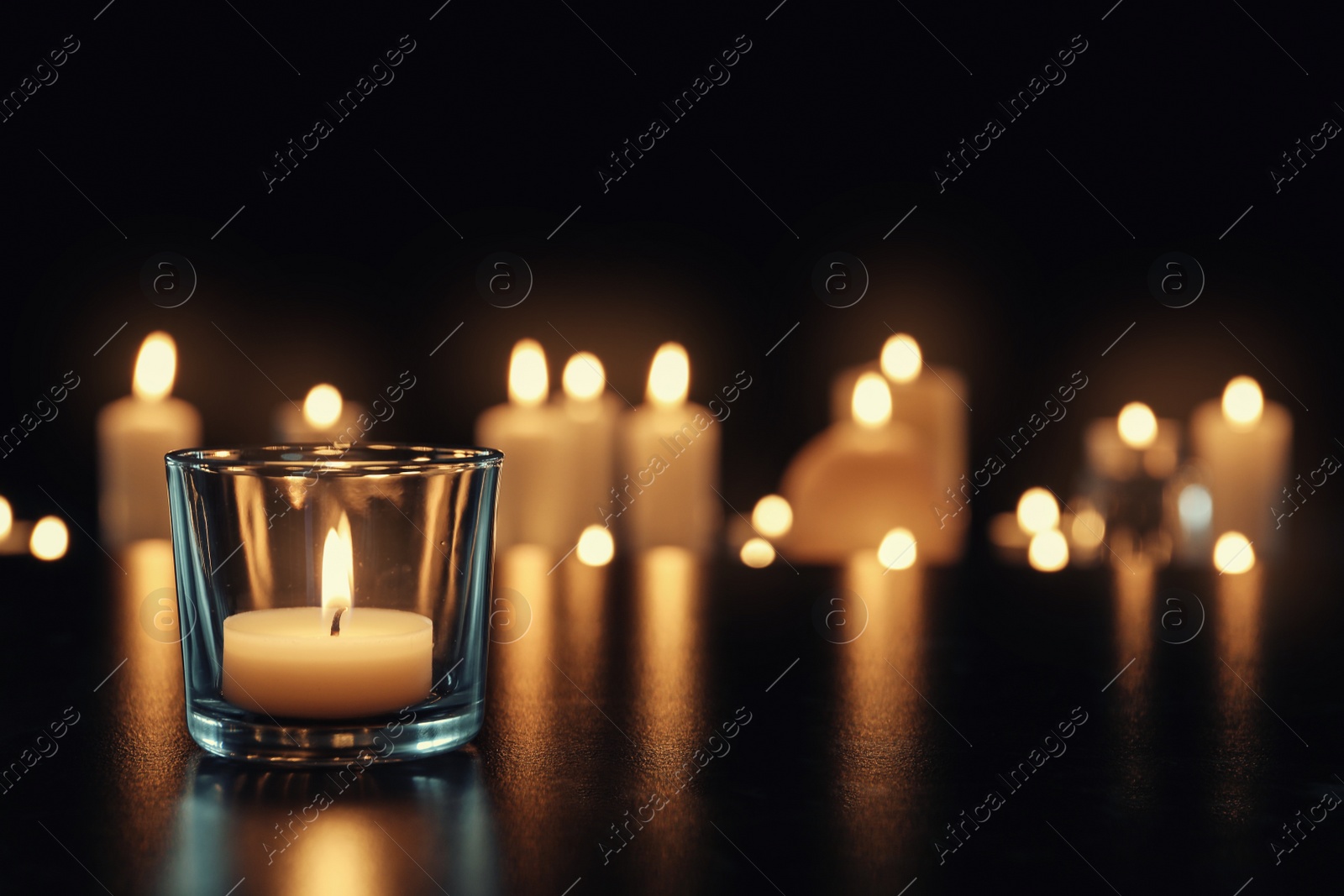 Photo of Burning candle on table in darkness, space for text. Funeral symbol