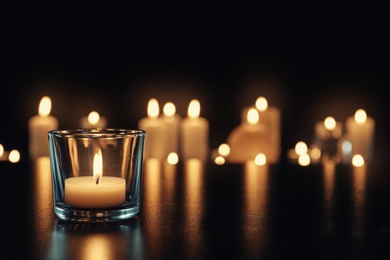 Photo of Burning candle on table in darkness, space for text. Funeral symbol