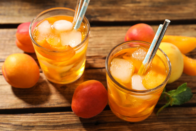 Photo of Delicious refreshing drink with apricot on wooden table, closeup