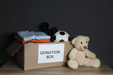 Donation box with clothes and toys on table against black background