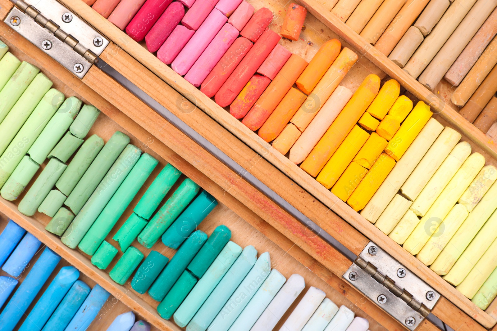 Photo of Set of soft pastels in wooden box as background, top view. Drawing material