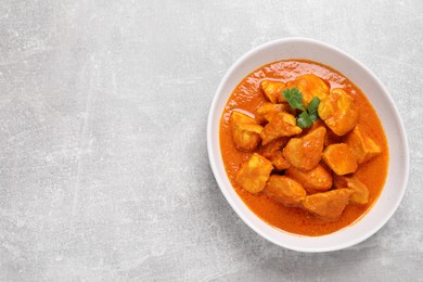 Bowl of delicious chicken curry on light grey table, top view. Space for text