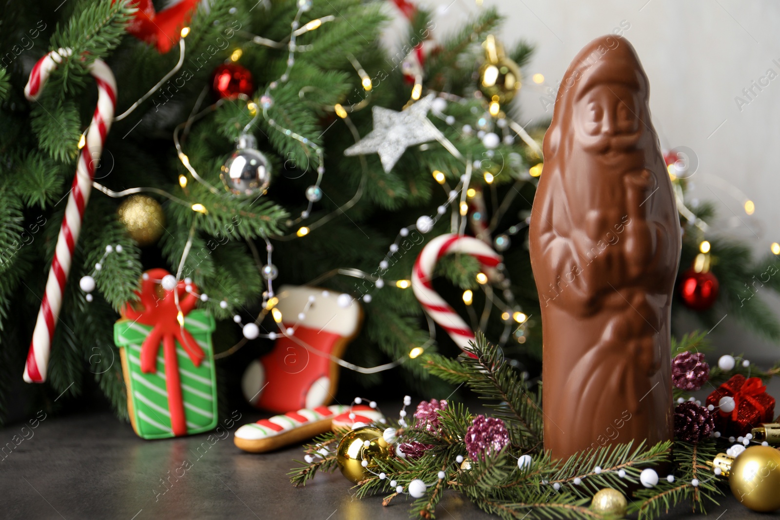 Photo of Chocolate Santa Claus and decorations on table near Christmas tree, space for text