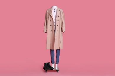 Photo of Female mannequin with boots dressed in stretch coat, jeans and shirt on pink background. Stylish outfit